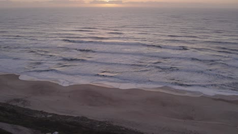 Reveal-shot-of-campervans-standing-at-Praia-da-Areeira-Portugal-at-sunset,-aerial