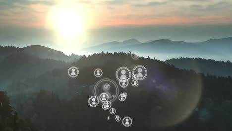 animation of multiplying people icons moving over idyllic misty mountain landscape at sunset