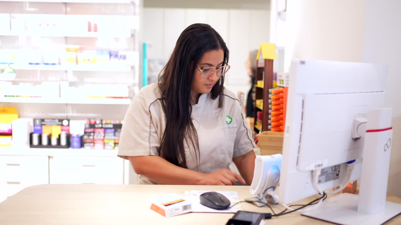Pharmacist working on computer at pharmacy counter