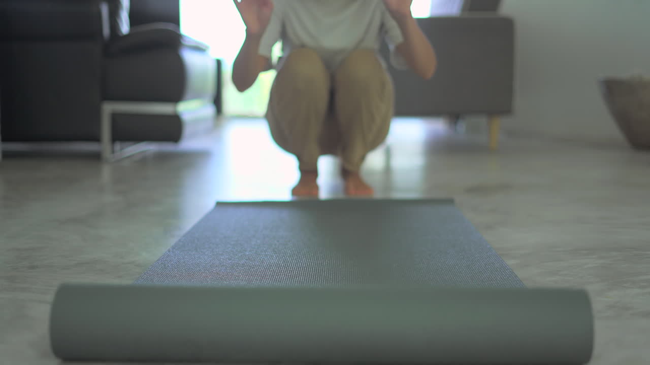 Woman rolling out yoga mat in living room