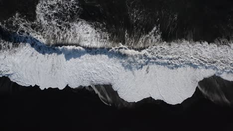 breaking waves at black sand beach in island