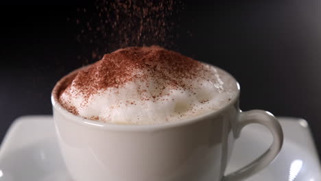 Cappuccino-coffee-pouring-cocoa-on-black-background