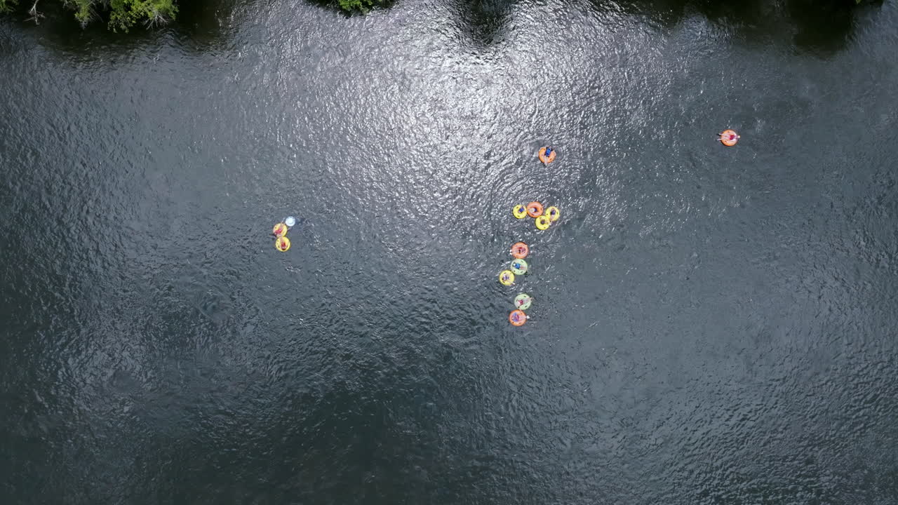 Top down aerial drone footage that is following people floating down the Hiawassee River in inner tubes in Tennessee during the summer months.
