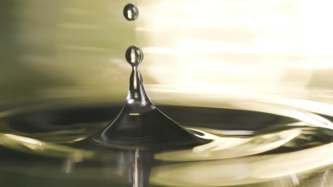 Water single drop falling down in golden liquid surface super slow motion, Extreme Macro