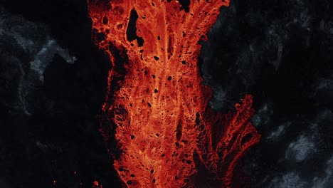 red burning lava river surrounded by dark basalt rock, top down