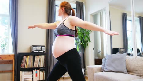 mujer embarazada practicando yoga en la sala de estar
