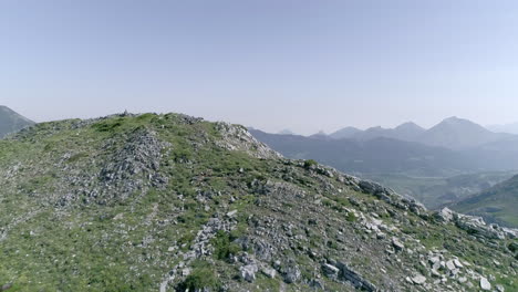 Epic-aerial-shot-cresting-over-a-rocky-peak-to-reveal-a-picturesque-green-valley-surrounded-by-beautiful-scenic-mountains,-Mampodre-Massif,-Leon,-Spain