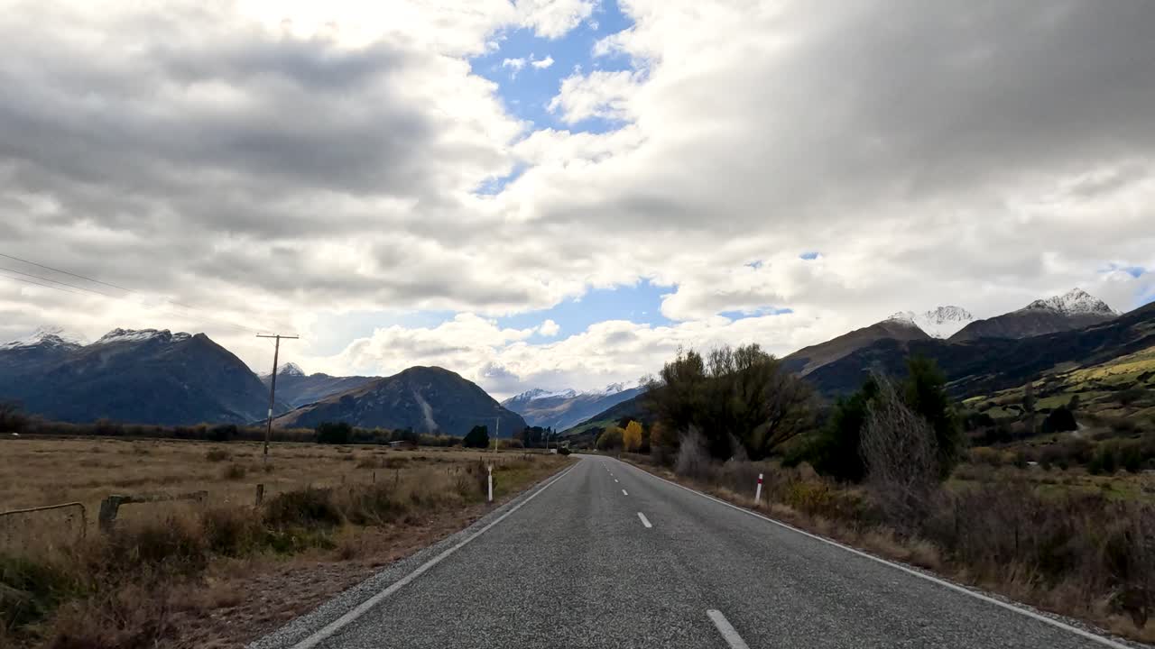 Point-of-view drive along rural road, overcast sky, mountain landscape, steady camera, natural lighting