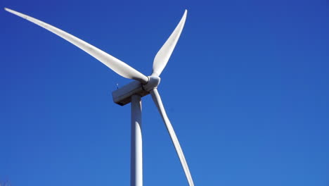 a wind turbine spins on a sunny, clear autumn day