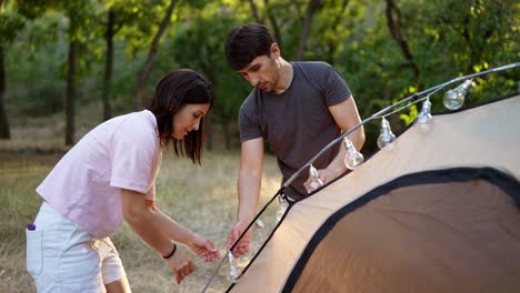 couple setting up tent in a forest