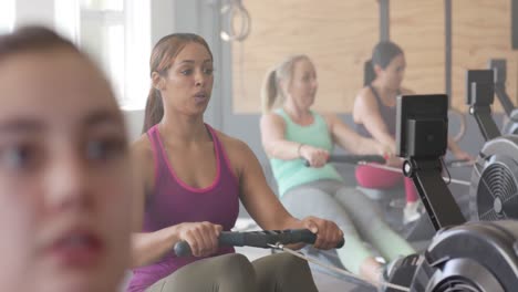 Konzentrierte,-Unveränderte,-Vielfältige-Frauen,-Die-In-Zeitlupe-Auf-Rudergeräten-Im-Fitnessstudio-Trainieren