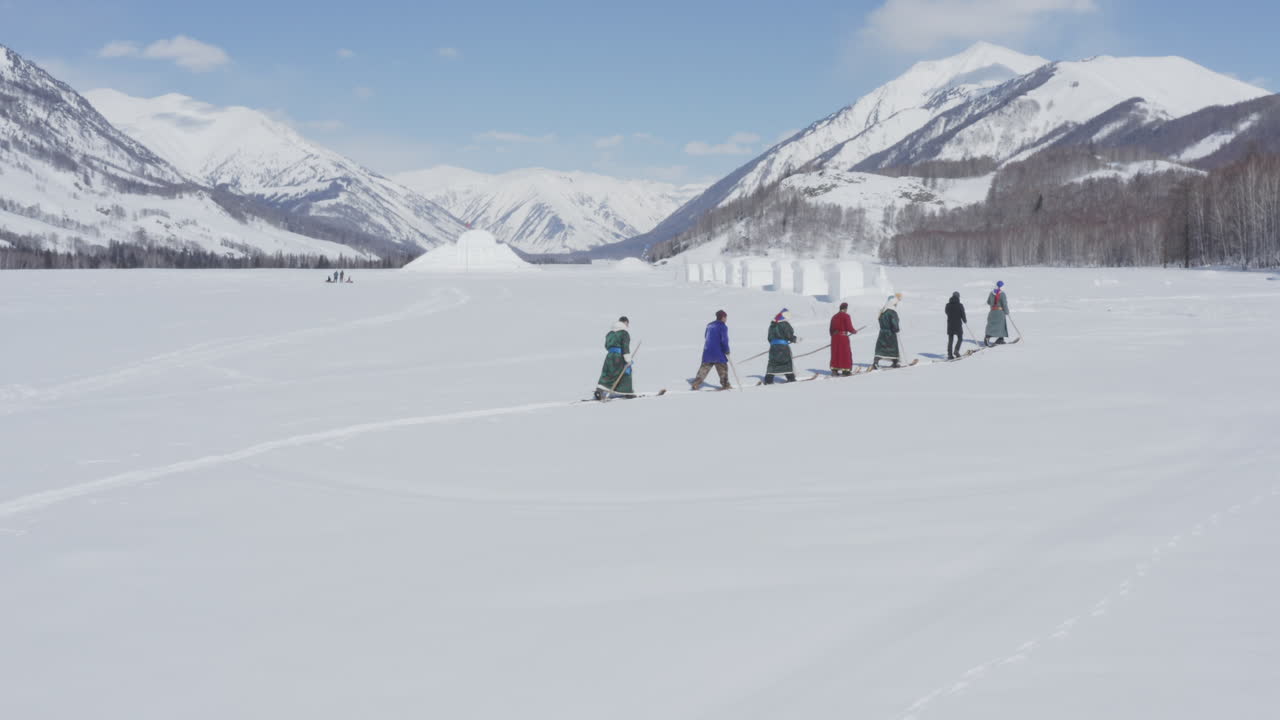 Tuva men history reenactment, hiking up snow mountain in ancient fur skis. Hemu Village, Xinjiang, China