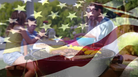 family enjoying a picnic and the american flag for fourth of july.