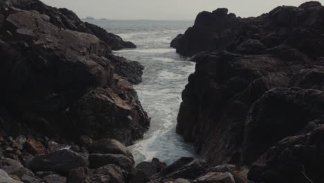 stationary shot of waves crashing through large rocks in ucluelet bc