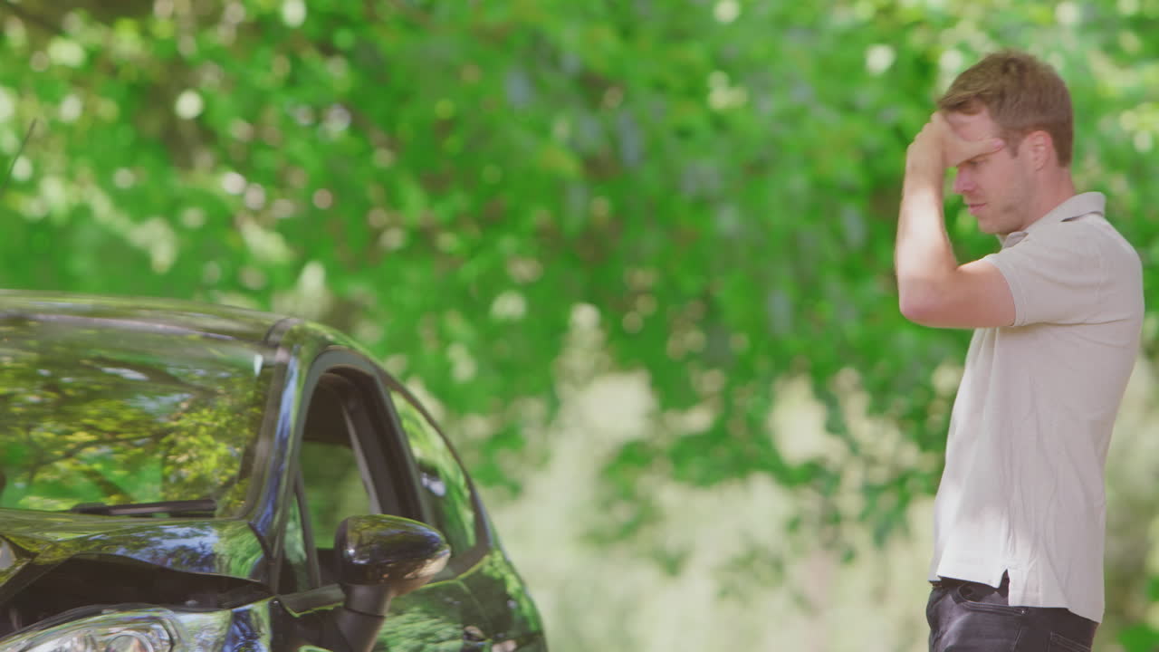 사람이 담배를 피우는 차에서 나와 응급 서비스에 전화하기 전에 사고 피해를 검사합니다.