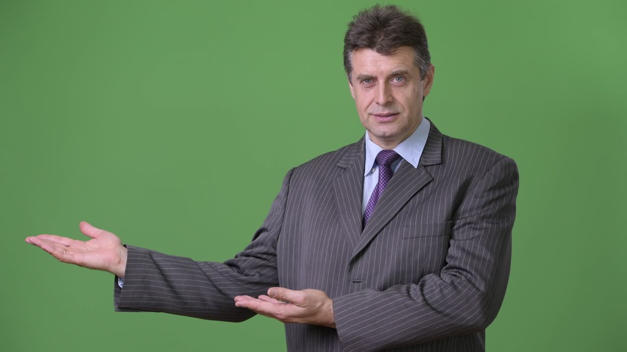 Mature handsome businessman against green background