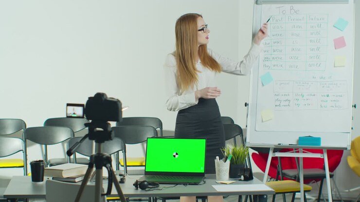 A woman is conducting an e-lesson from an empty classroom. Remote education, online education, remote studying, online learning concept. Green Screen Chroma Key Laptop for Learning.