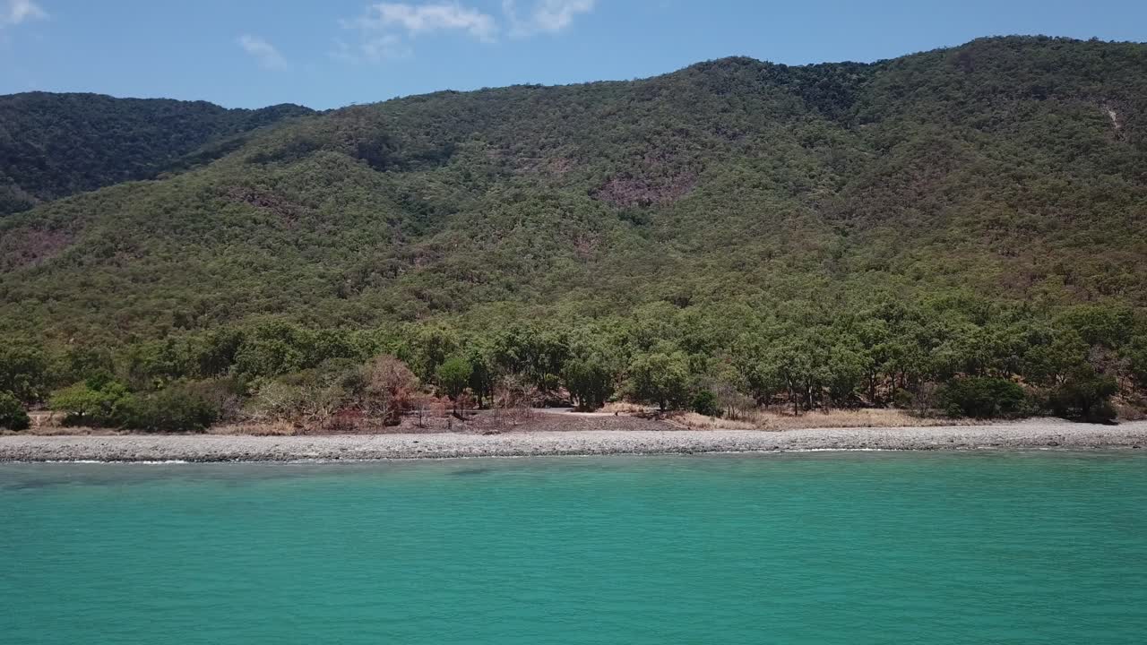 drone moviéndose lateralmente sobre la playa tropical y el lado de la montaña