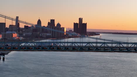 white truck crossing ambassador bridge at sunrise with detroit skyline and the river in the background