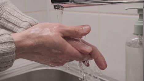 man washing her hands with liquid soap in the bathroom