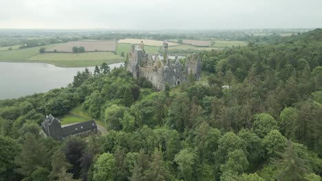 ancient castle ruin surrounded by forest next to a lake