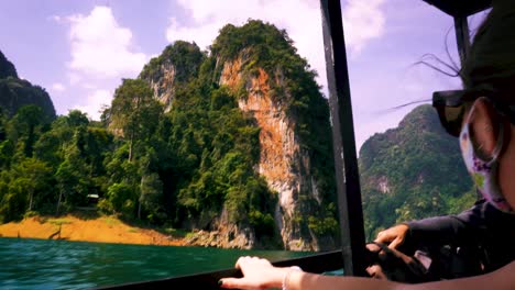 Female-Traveller-Wearing-Face-Mask-Looking-Out-From-Boat-Going-Past-Along-On-Cheow-Lan-Lake