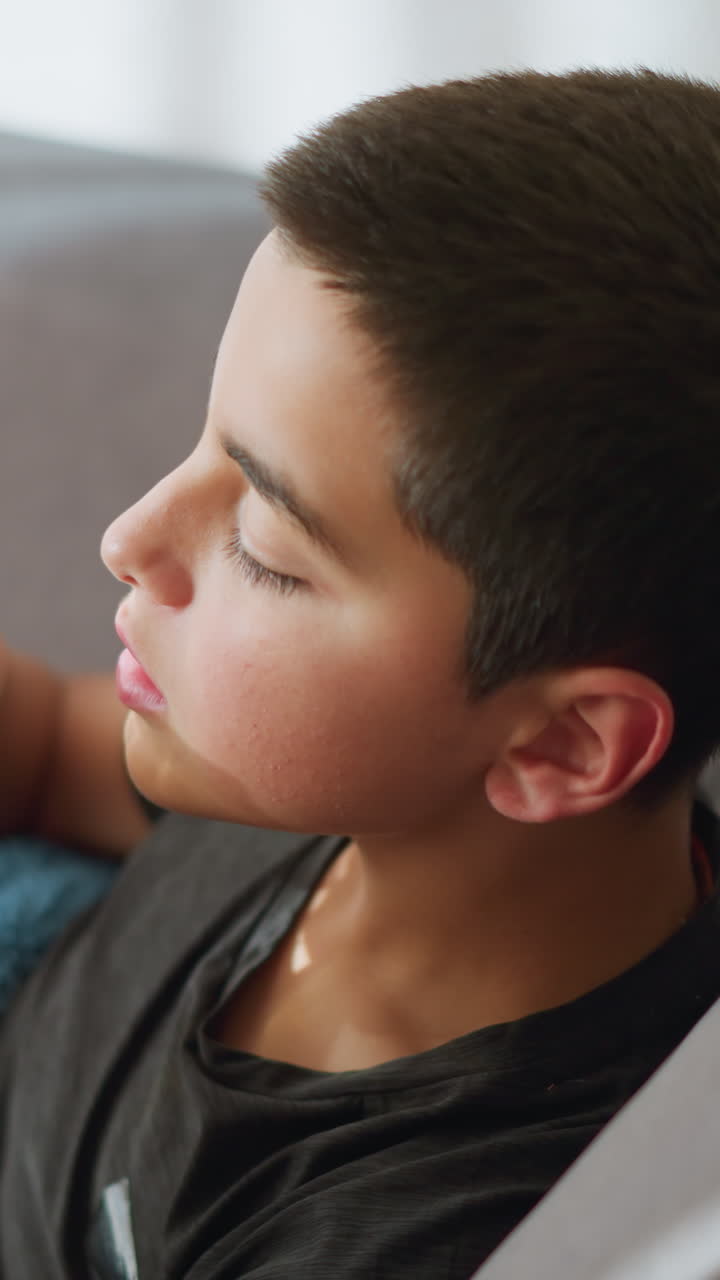 Close up of caregiver handing over tea to sick boy lying on the couch, boy is collecting the cup from the caregiver in a caring moment while recovering