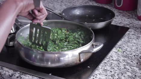 woman cooking collard greens in skillet