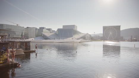 floating saunas on oslo harbour promenade waterfront, people diving into fjord