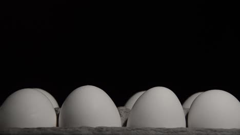 bandeja de huevos de pollo blancos en una habitación oscura que está iluminada por una linterna de búsqueda, cerca