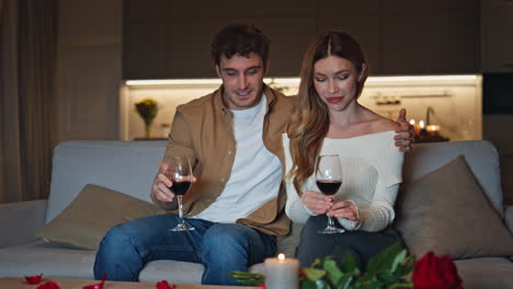 romantic guy embracing girl shyly in cozy candles living room. cute couple date