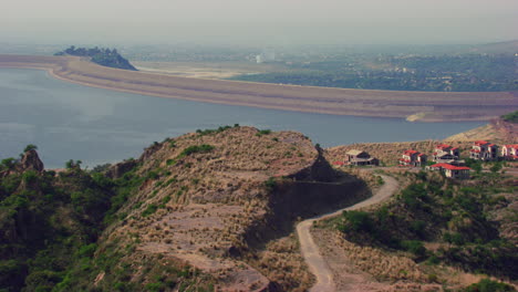 Una-Vista-Aérea-De-Irlanda-Con-La-Cima-De-Una-Colina,-Que-Muestra-Casas-Y-Bosques-Con-Una-Autopista-Sobre-El-Río,-Una-Gran-Vista-De-La-Ciudad-En-El-Fondo