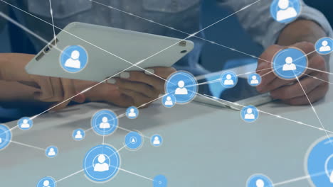 Animation-of-network-of-connections-with-icons-over-diverse-business-people-with-tablet