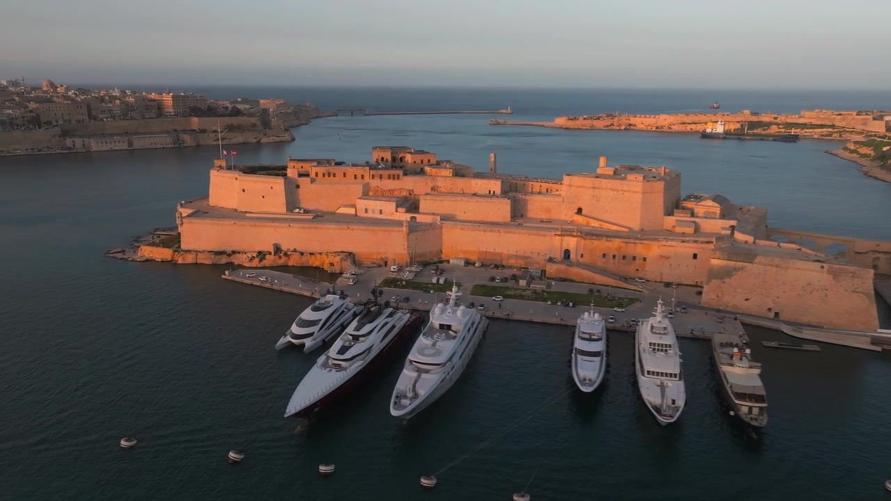 Pemandangan Udara Drone Valletta, Malta, Birgu, Tiga Kota Menghadap Grand Harbour Saat Jam Emas. Garis Langit Tepi Laut Bersejarah, Pemandangan Pelabuhan, dan Cahaya Senja Hangat di Seluruh Ibu Kota
