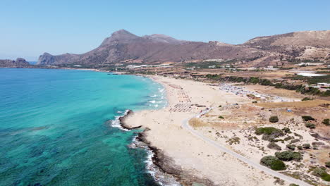 vista aérea que orbita la idílica playa de falassarna, creta con turistas tomando el sol y nadando en el mar egeo azul