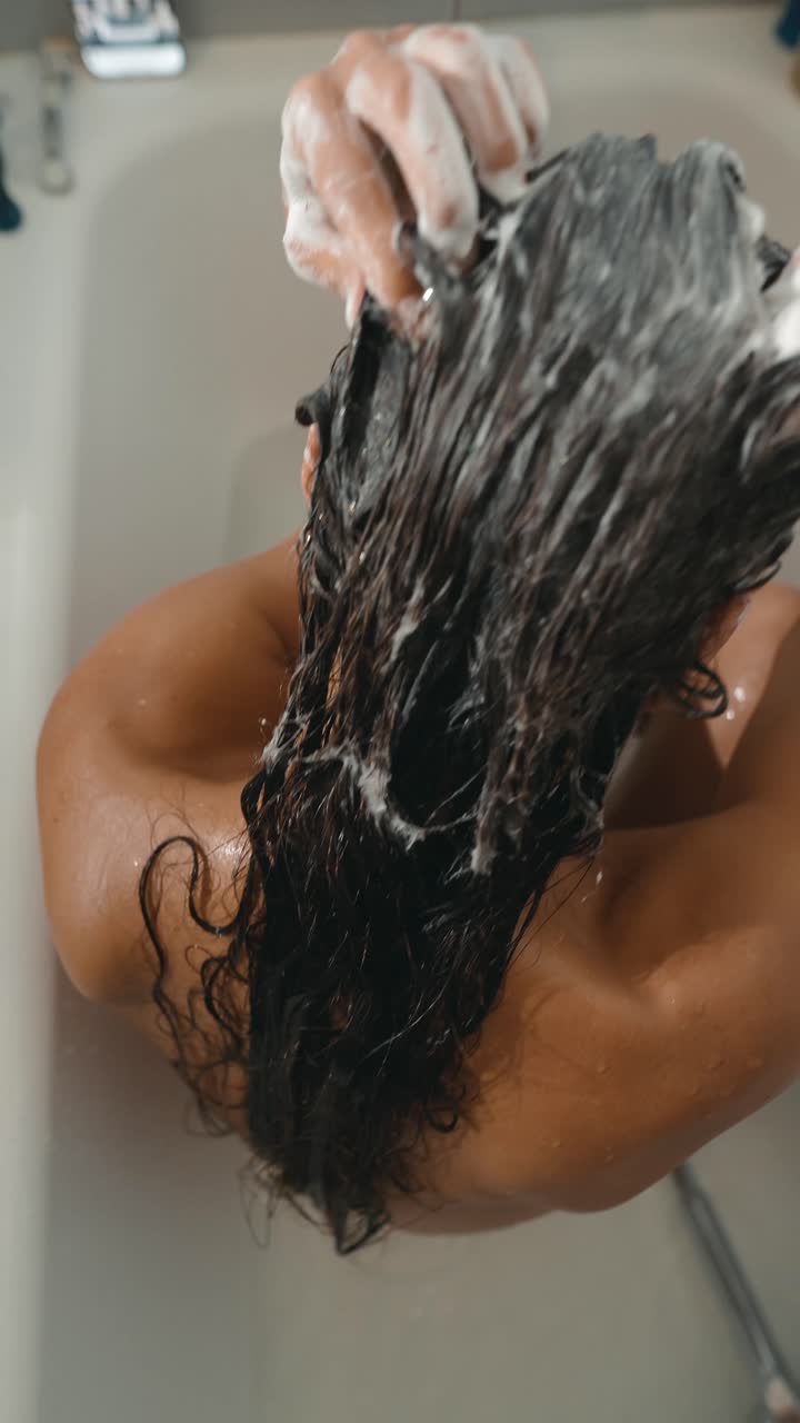 Woman washing hair in bathtub
