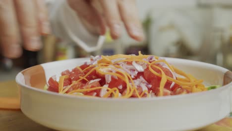 chef adds carrot slices on top of vegetable salad