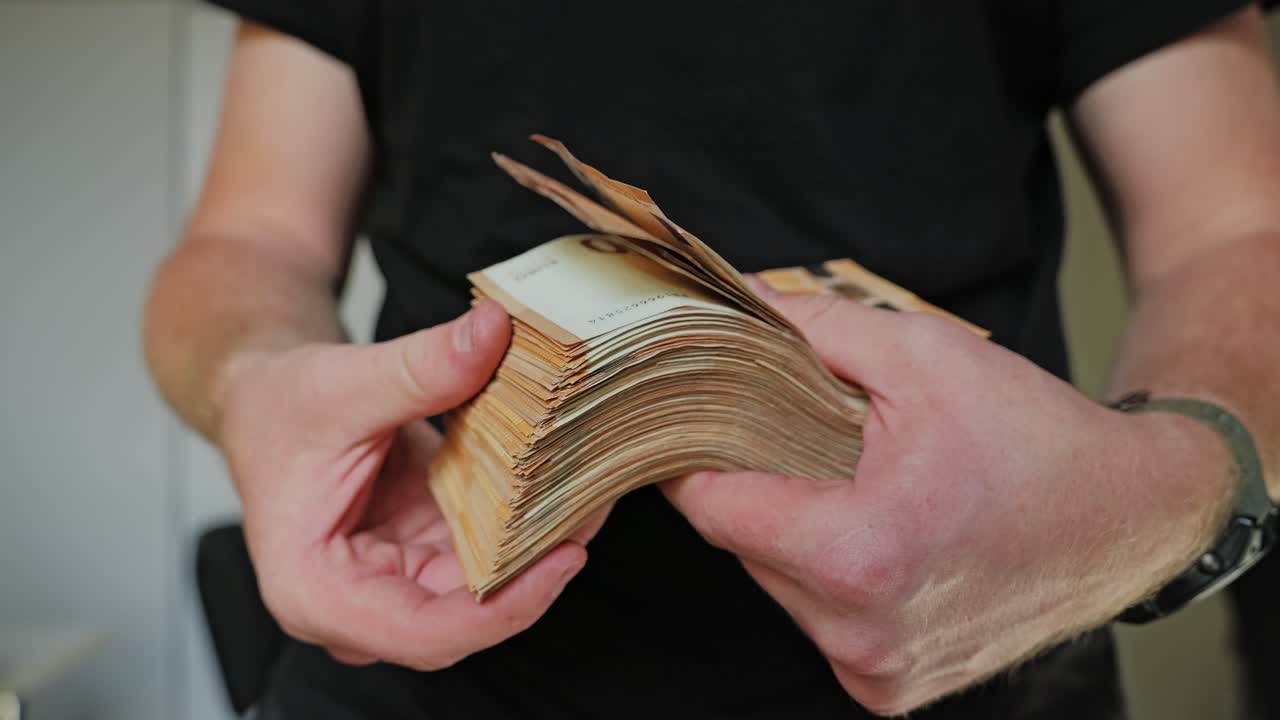 Man flips through thick euro cash stack, flaunting wealth in slow motion