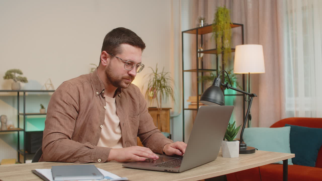 Excited young caucasian man working on laptop shocked by sudden victory sitting at home office table