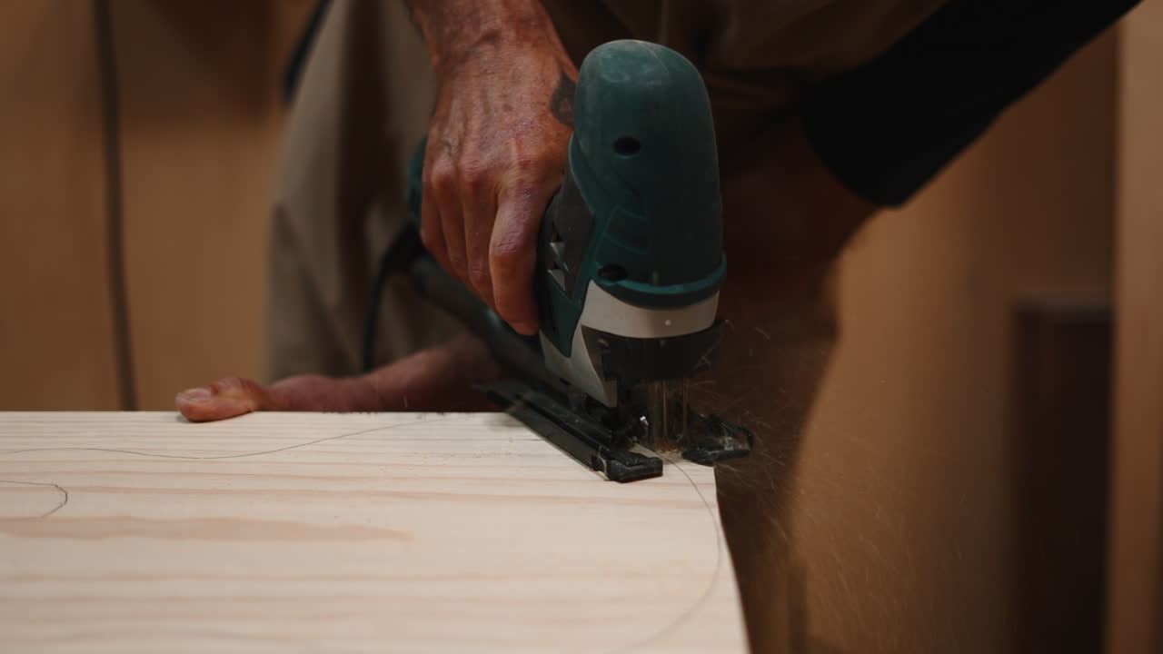 Primo piano di un artigiano che taglia il legno con un seghetto alternativo