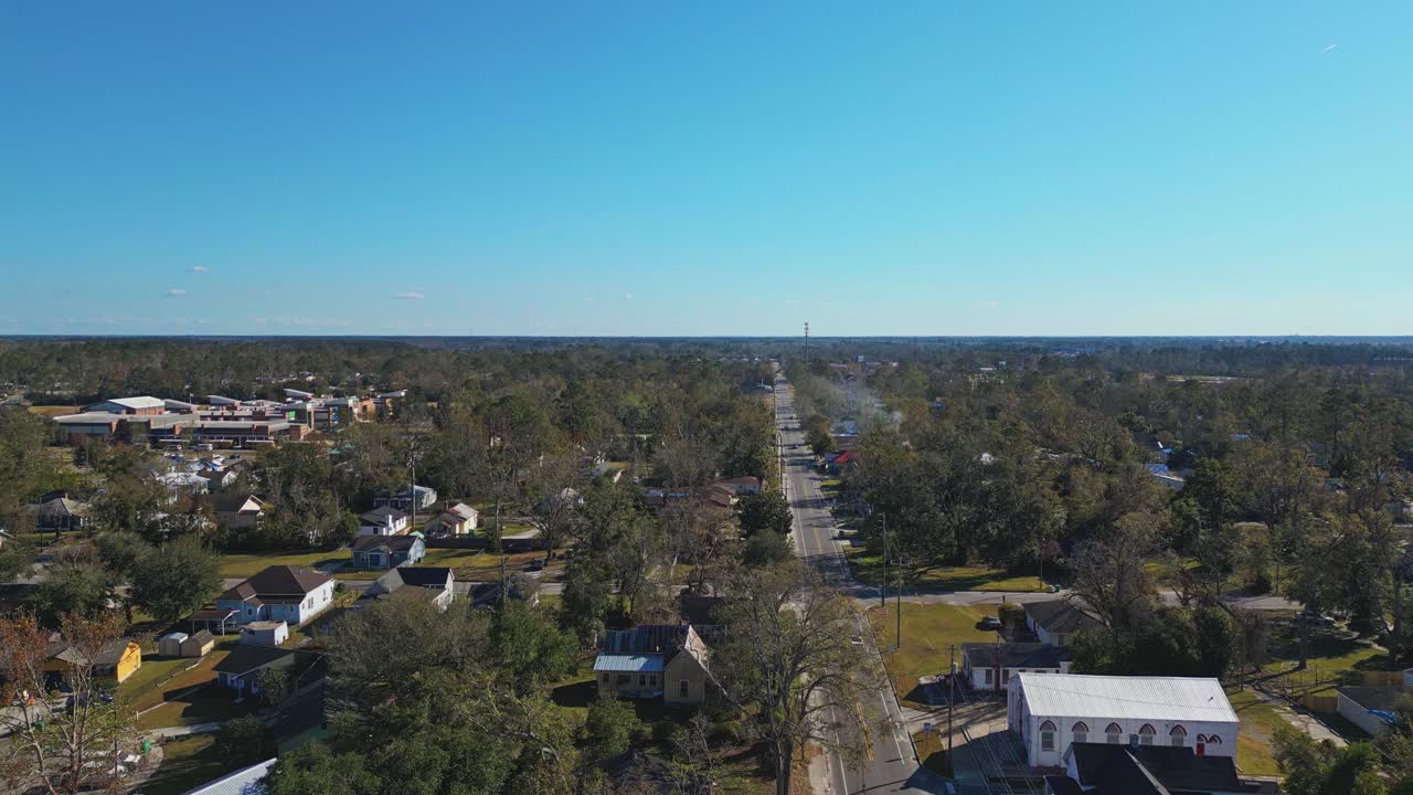 Main street of american town in Georgia during sunny day with blue sky. Aerial forward wide shot. Houses and homes in Suburb of Valdosta.