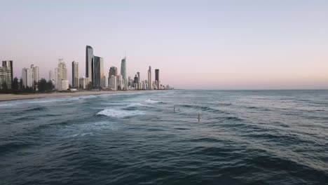 Drohnen-Luftparallaxe-Mit-Stand-Up-Paddle-Boardern-Am-Strand,-Die-Wellen-Reiten