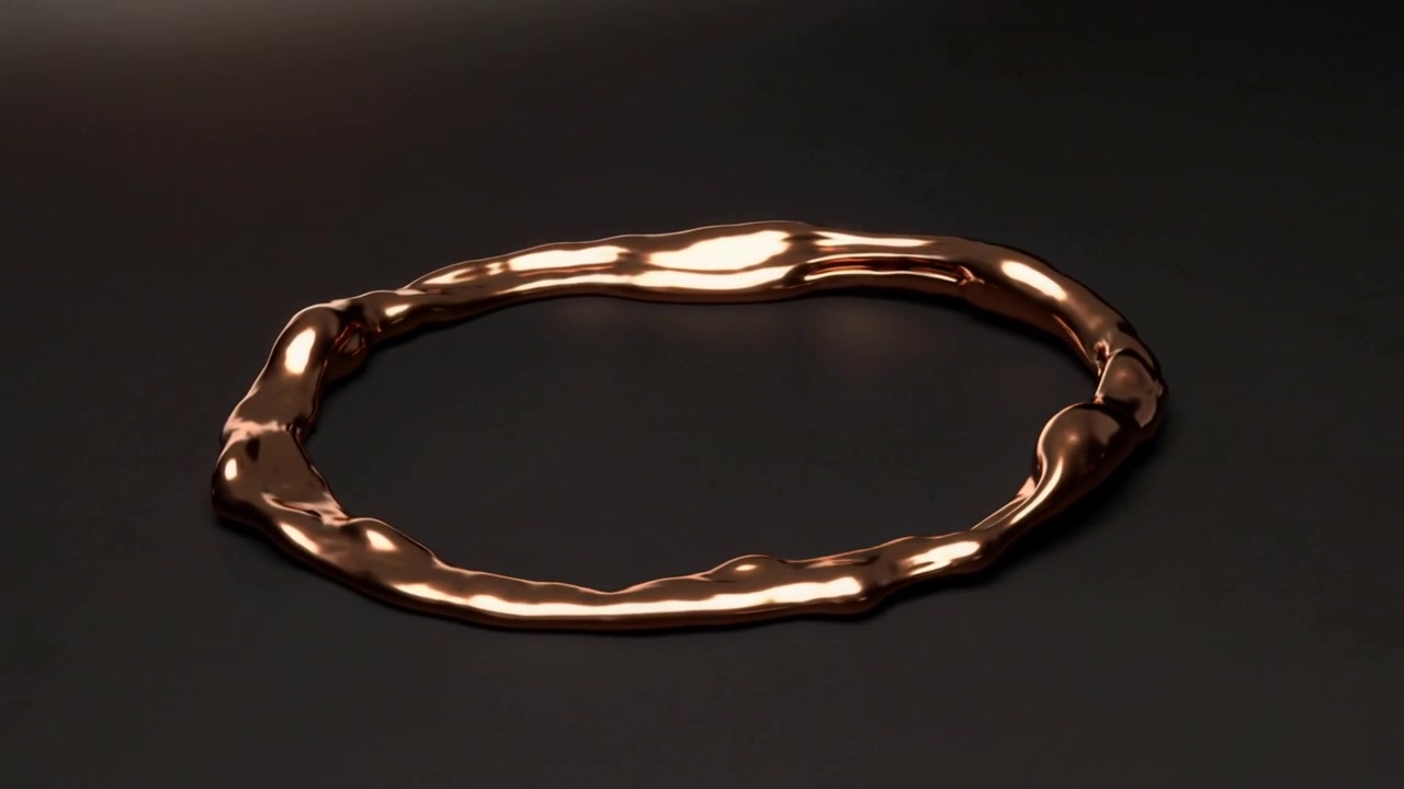 Anello di rame rotante che rivela una superficie ondulata con luce da studio mutevole che crea riflessi sul palco