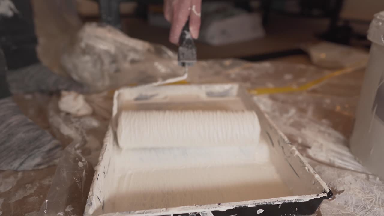 hombre blanco mano rodando extendiendo pintura blanca en la bandeja con el mango del rodillo de pintura en la habitación casa cambridge inglaterra