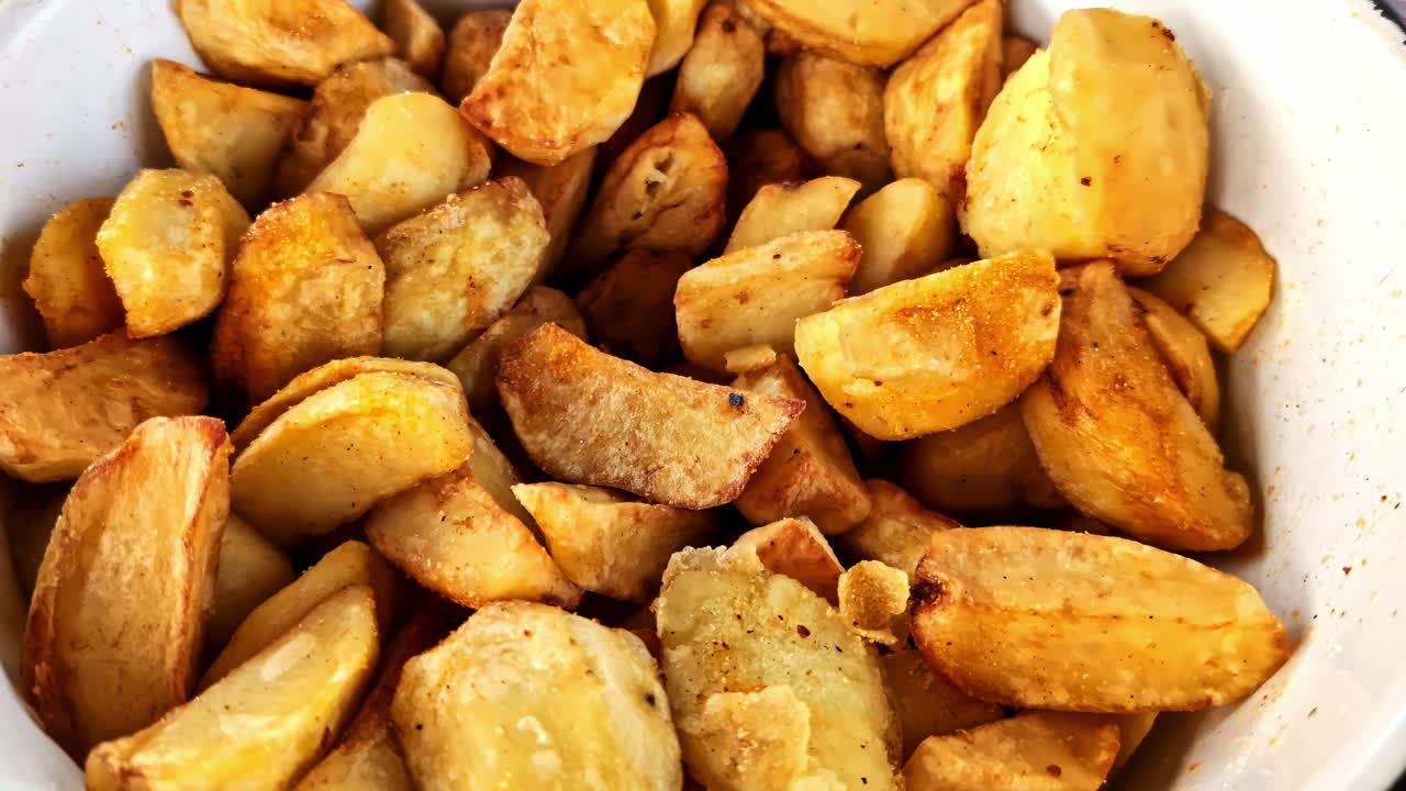 Bowl of golden roasted potatoes with seasoning for outdoor picnic in closeup