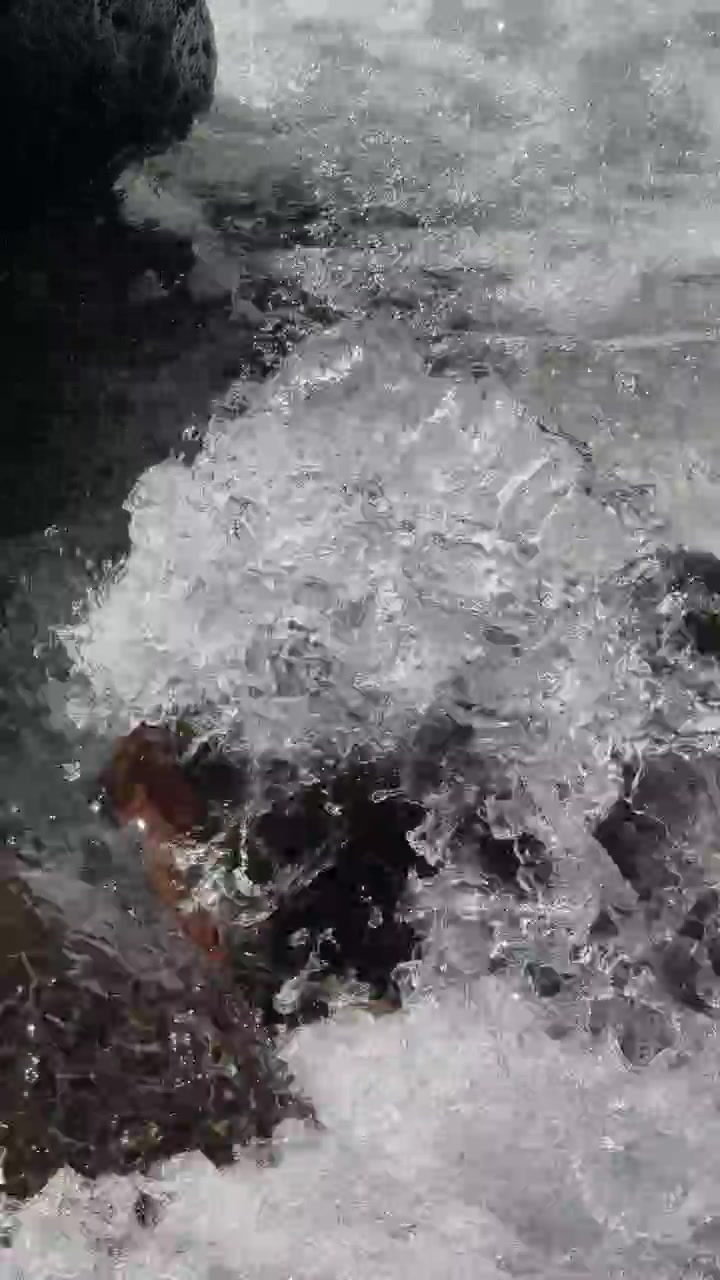 Acqua limpida che scorre impetuosa su rocce scure in un ruscello di montagna.