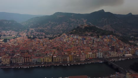 Aerial-of-Bosa,-a-beautiful-old-holiday-village-in-Sardinia-close-to-Alghero-in-Italy,-a-masterpiece-of-mediterranean-historic-architecture-in-the-idyllic-landscape-by-the-sea