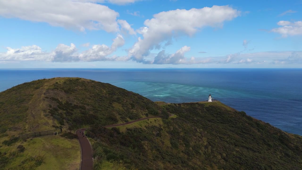Upward drone following shot the scenic Aupouri Peninsula coastal ridge trail overlooking Cape Reinga or Te Rerenga Wairua in the popular tourist destination, Northland, New Zealand