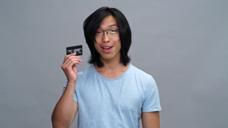 handsome young asian man showing credit card