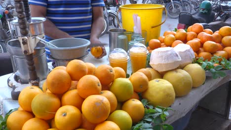 man peel an orange at a stand with lots of oranges for orange juice at saddar bazar street of karchi